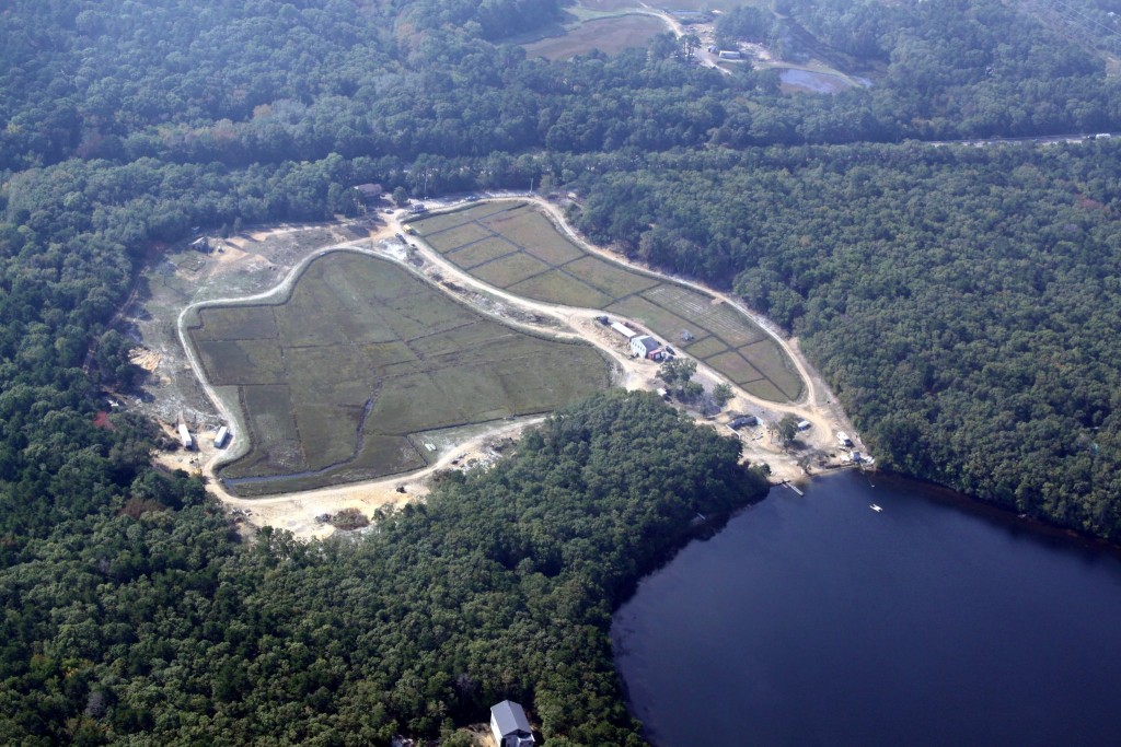 aerial view of large 17 acre cranberry farm on edge of pond with beach